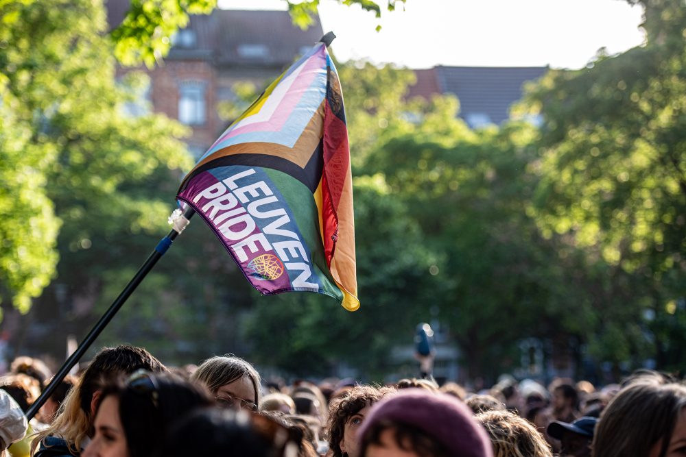 Bei einem Umzug wird eine Regenbogen-Flagge mit der Aufschrift "Leuven Pride" hochgehalten