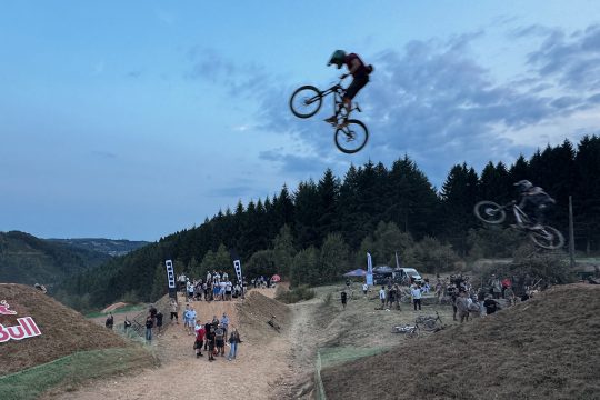 Zwei Freerider springen durch die Luft, von unten schauen Menschen hoch