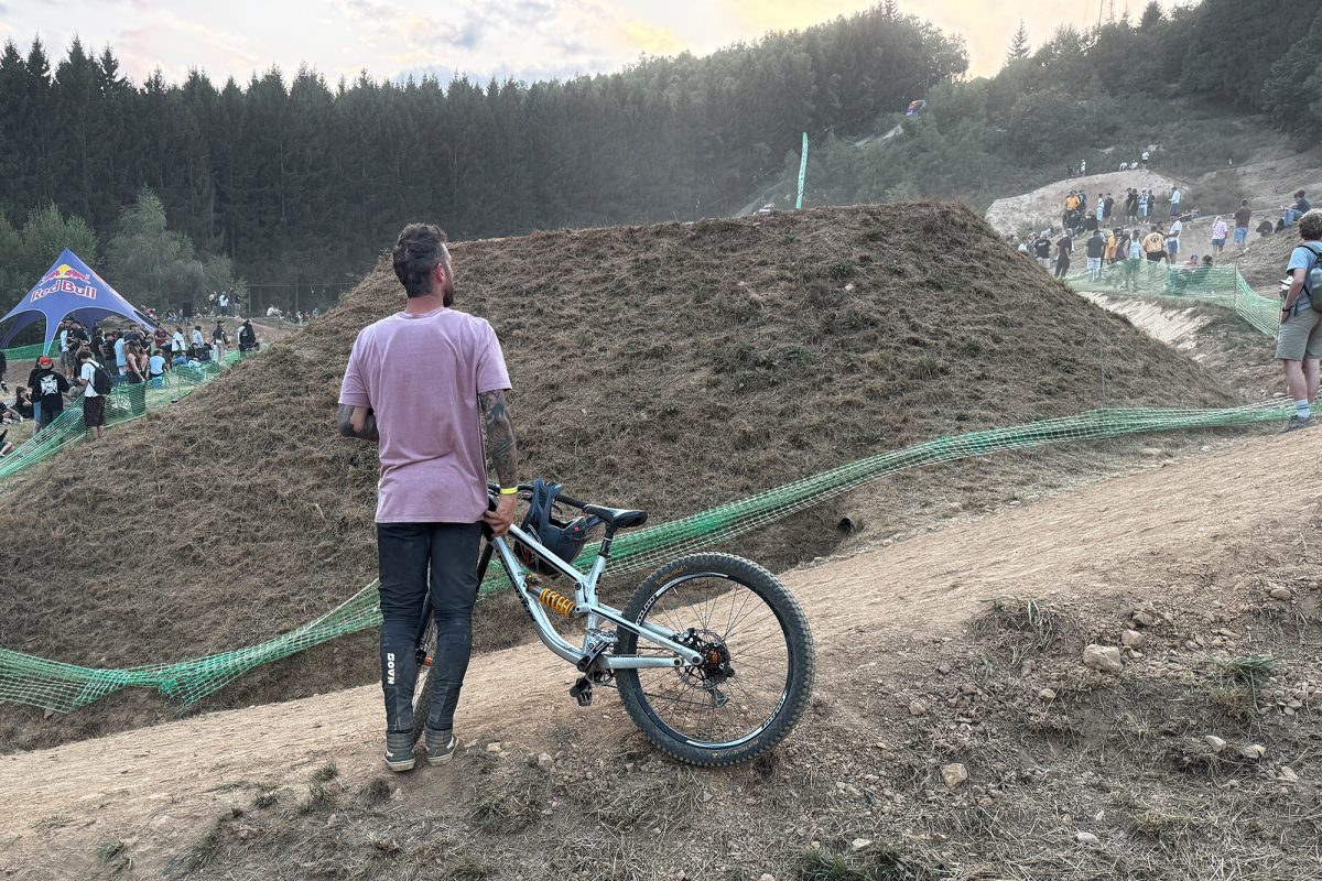 Mann mit Mountainbike steht vor Hügel und schaut nach vorn