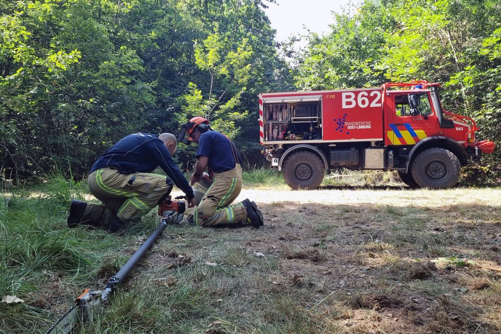 Feuerwehrleute arbeiten an Schläuchen, im Hintergrund ein Fahrzeug der Feuerwehr