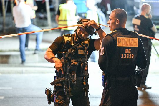Bewaffnete Polizisten stehen in der Nähe des Tatorts
