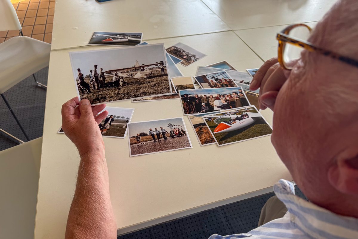 Manfred Schultz schaut sich historische Fotos an, die auf einem Tisch liegen
