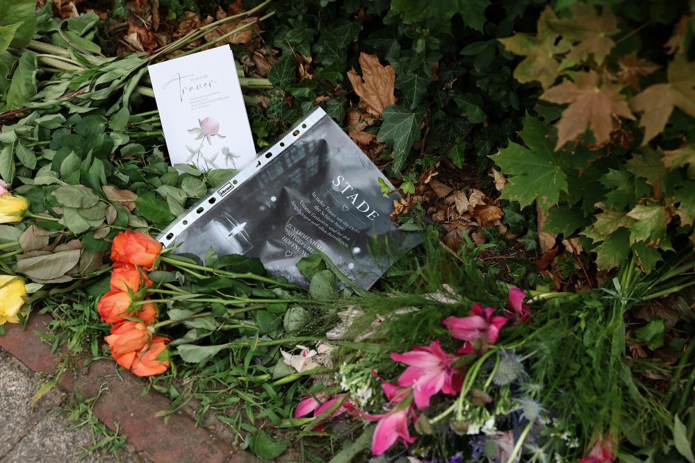 Menschen haben Blumen und Beileidsbekundungen vor dem Tatort abgelegt