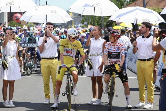 Pogacar und Vingegaard werden mit Sonnenschirmen beschützt vor dem Start der neunten Etappe der Tour de France in Malemort