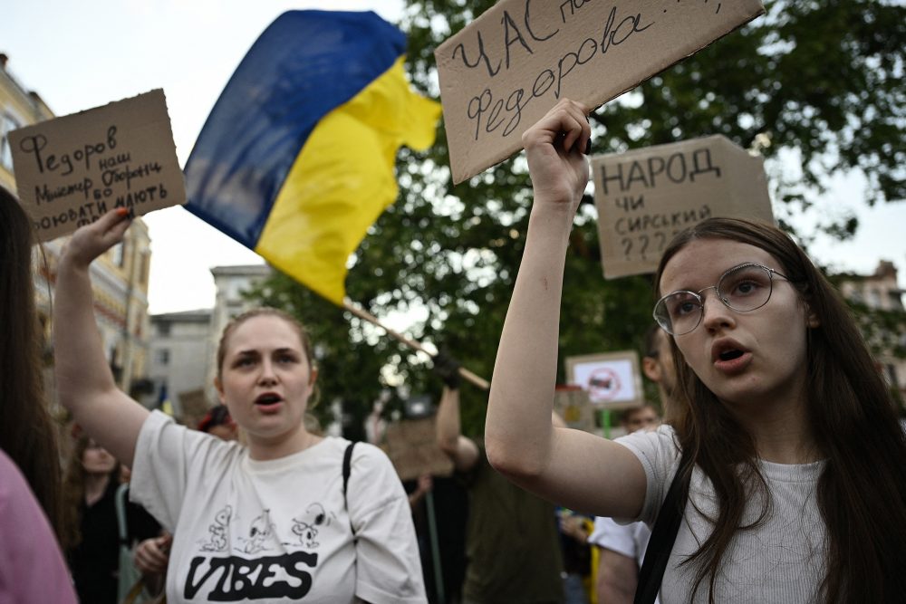 Menschen protestieren mit selbstgeschriebenen Plakaten und Ukraine-Flaggen