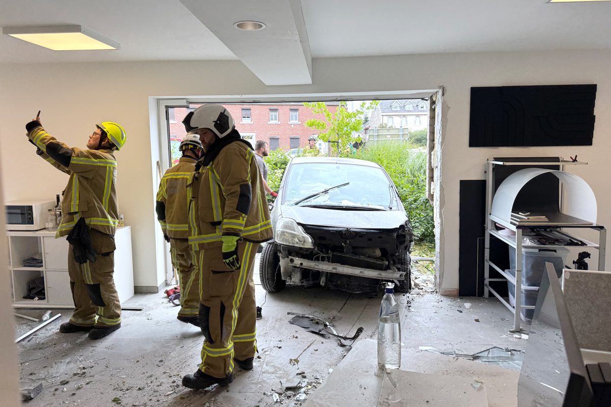 Feuerwehrleute begutachten die Schäden, im Hintergrund sieht man das Unfall-Auto