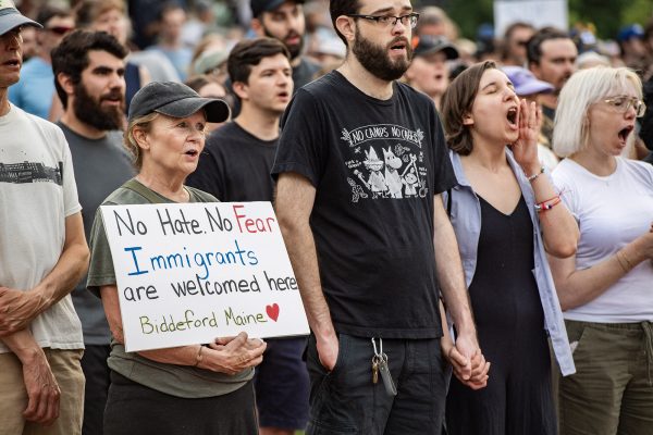 Menschen bei einer friedlichen Mahnwache zu Ehren des erschossenen Kolumbianers. Eine Frau hält ein Plakat mit der Aufschrift "Keine Angst, kein Hass. Migranten sind hier in Biddeford willkommen"