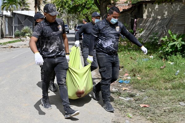 venezolanische Polizisten tragen eine mit einem grünen Tuch bedeckte Leiche eine Straße entlang