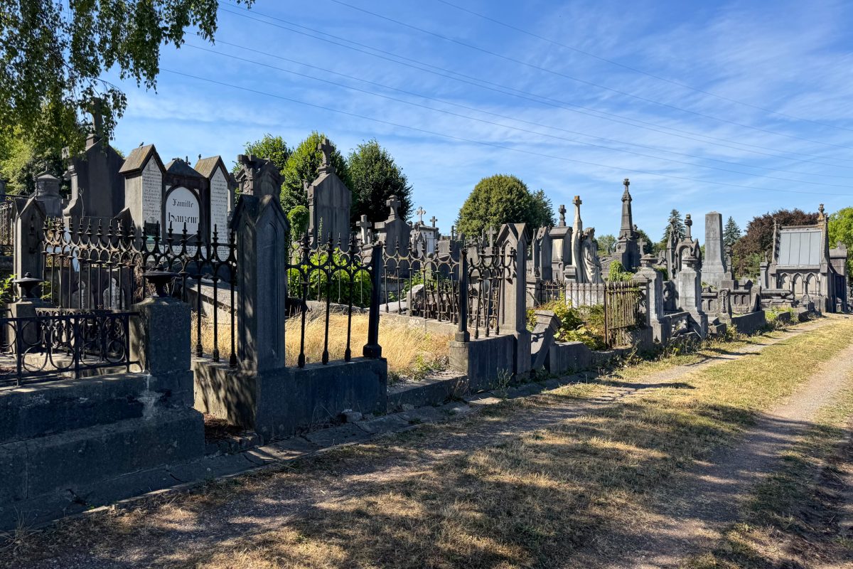 Weg auf dem Friedhof mit umzäunten Grabanlagen und Mausoleen