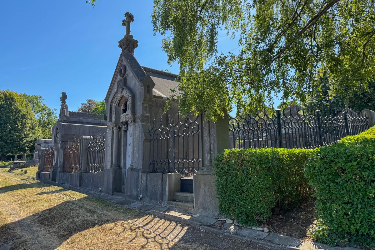 Weg auf dem Friedhof mit umzäunten Grabanlagen und Mausoleen