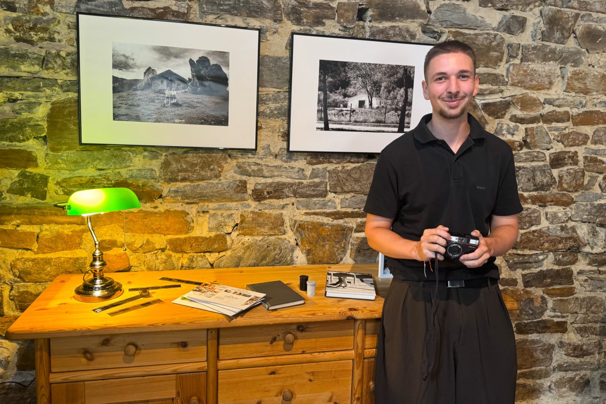 Joschua Heyen mit seiner Kamera vor zwei Fotos in der Ausstellung in der Stillen Post
