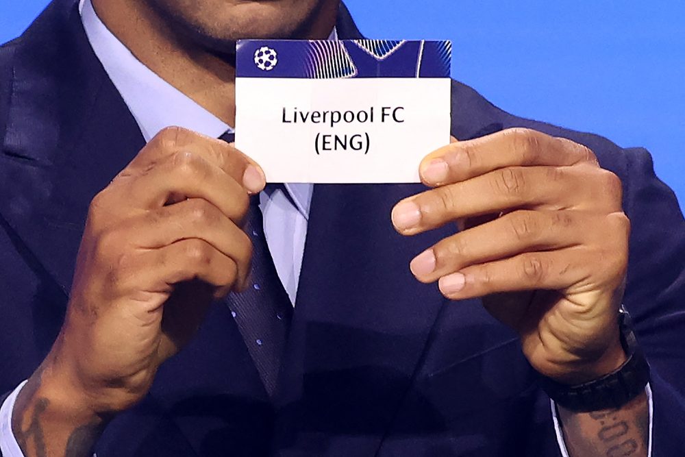 Mann hält einen Zettelm mit dem Namen Liverpool hoch