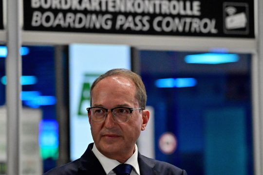 Deutschlands Innenminister Alexander Dobrindt am Flughafen Leipzig-Halle, im Hintergrund ein Schalter mit der Aufschrift "Bordkartenkontrolle"