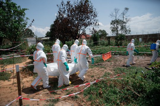 Helfer des Roten Kreuzes in Schutzausrüstung tragen den Leichnam eines Verstorbenen
