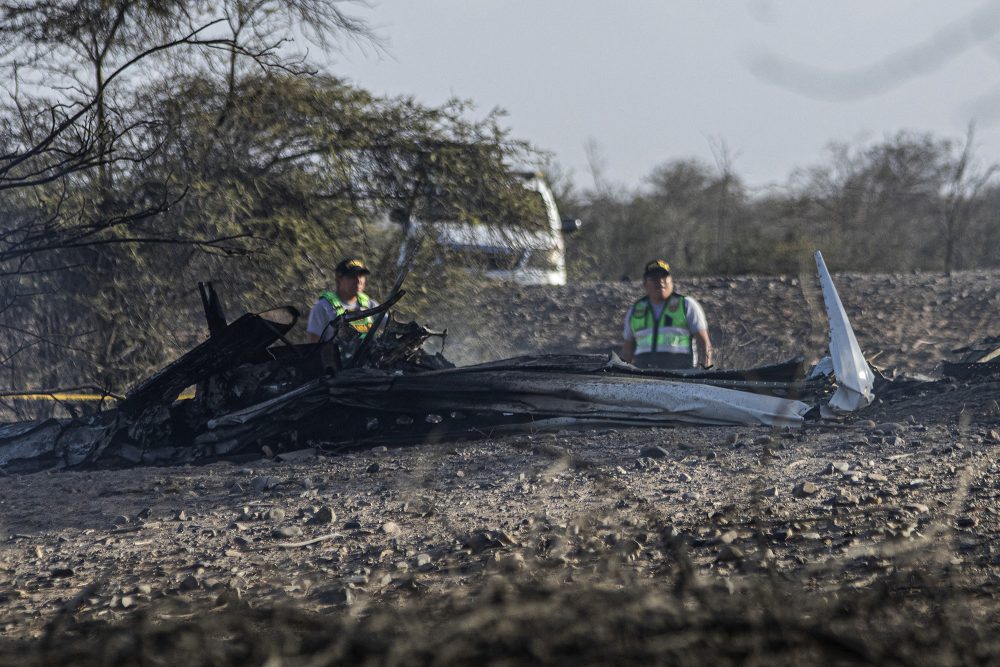 Teile des in Peru abgestürzten Kleinflugzeugs liegen auf dem Boden, zwei Einsatzkräfte stehen dahinter
