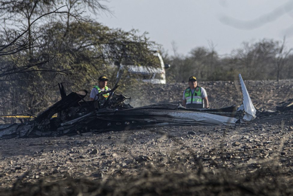 Teile des in Peru abgestürzten Kleinflugzeugs liegen auf dem Boden, zwei Einsatzkräfte stehen dahinter
