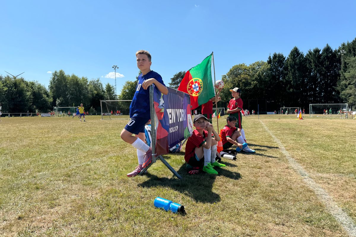 Junge Spieler unter anderem mit Portugal-Flagge am Spielfeldrand