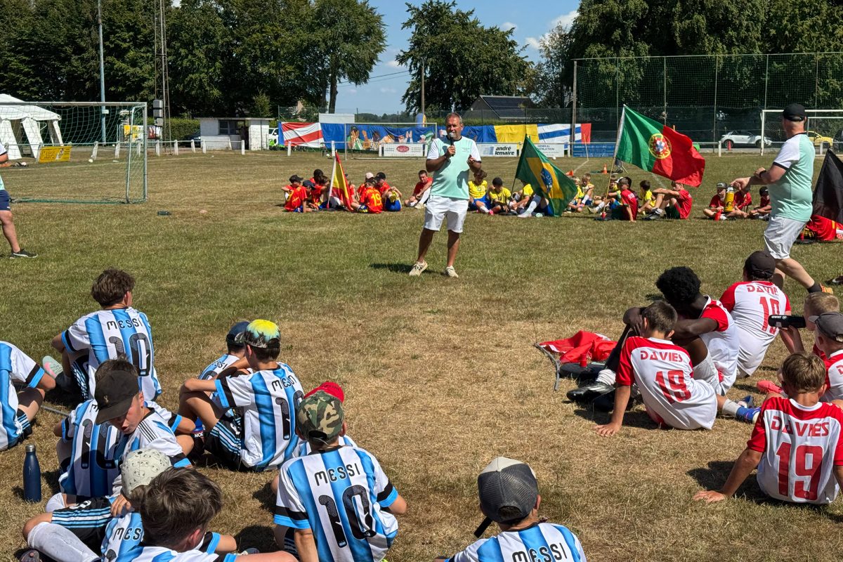 Die jungen Spieler sitzen auf dem Boden, ein Mann hält eine Ansprache