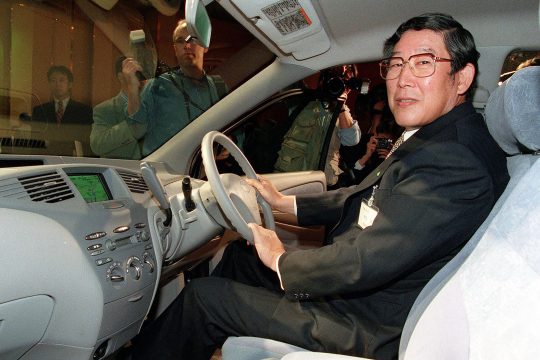 Der frühere Toyota-Chef Hiroshi Okuda sitzt hinter dem Steuer eines ausgestellten Fahrzeugs
