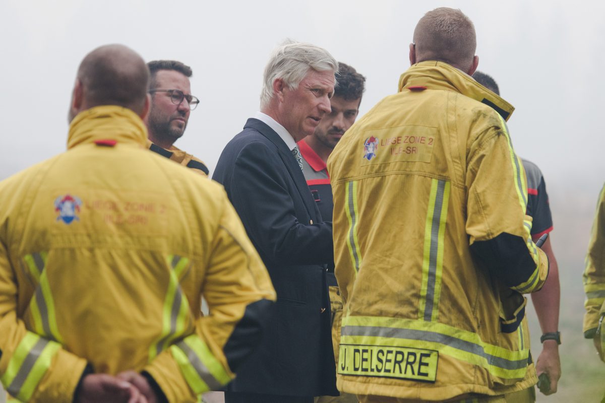 König Philippe hört Rettungskräften zu bei Erklärungen - im Hintergrund dichter Nebel