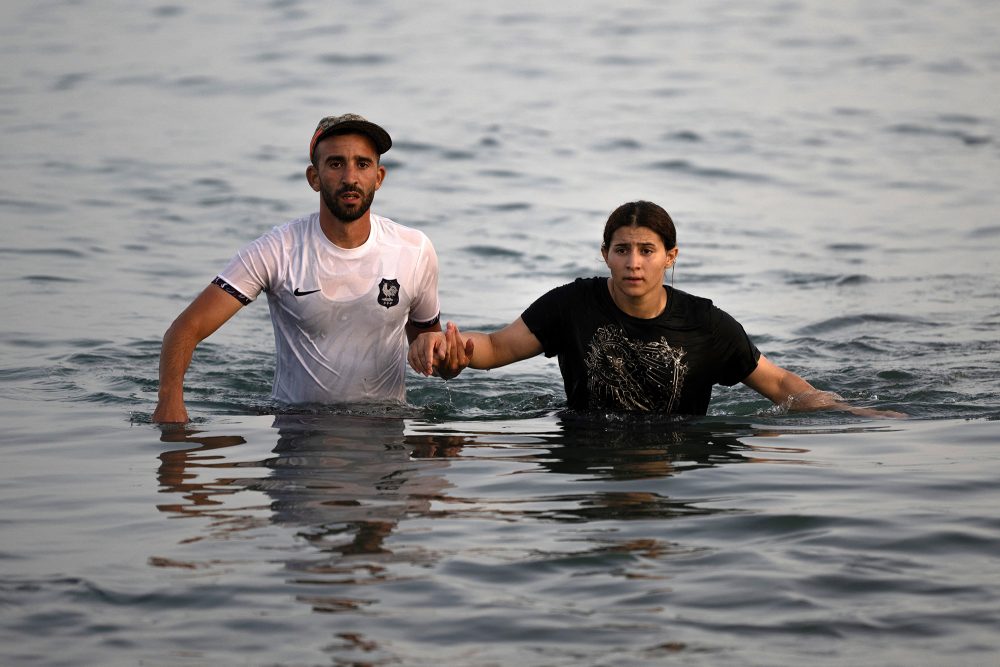 Zwei Migranten waten durch das Meer in Richtung Ceuta