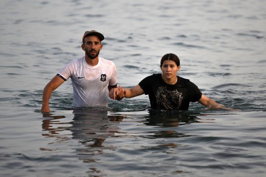 Zwei Migranten waten durch das Meer in Richtung Ceuta