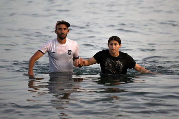 Zwei Migranten waten durch das Meer in Richtung Ceuta