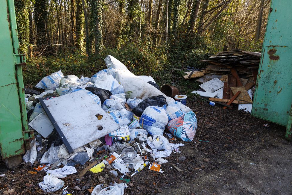 Wilder Müll liegt neben Müllcontainer
