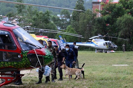 Nepalesisches Sicherheitspersonal und Spürhunde besteigen einen Hubschrauber, um Vermisste zu suchen