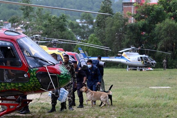 Nepalesisches Sicherheitspersonal und Spürhunde besteigen einen Hubschrauber, um Vermisste zu suchen