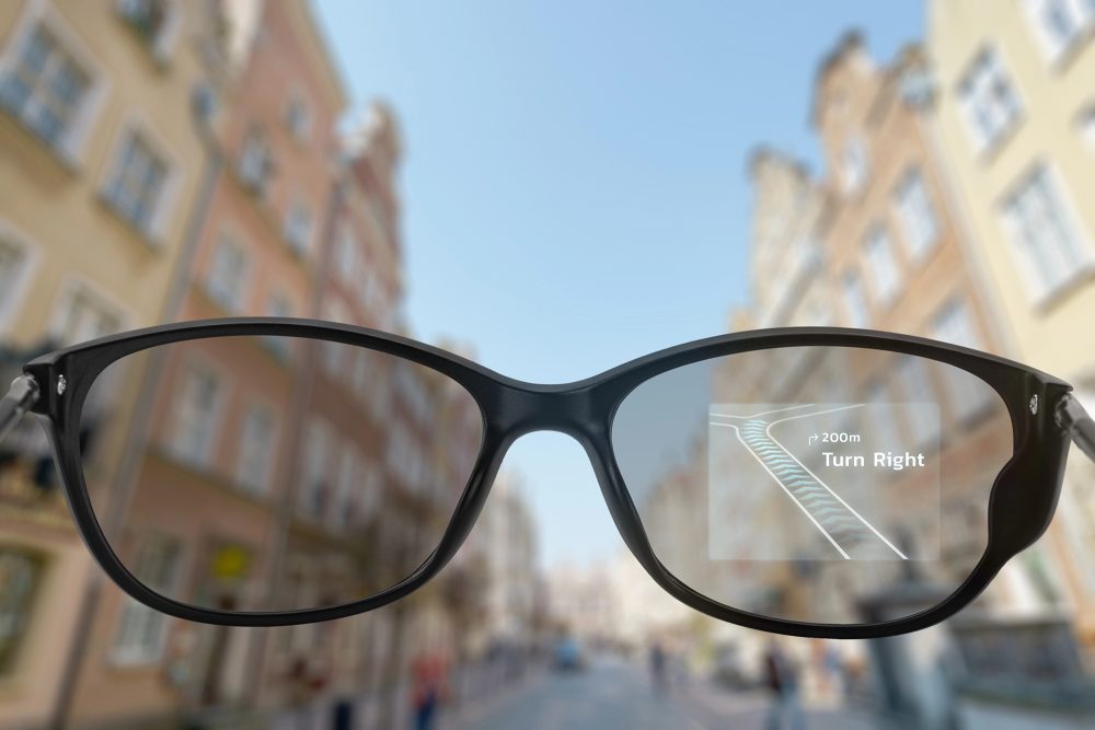 Navigations-App auf einer Smart-Brille, im Hintergrund eine Straße mit Passanten