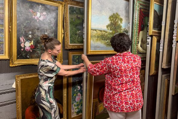 Mitarbeiterinnen verschieben die Kunstwerke auf dem Speicher