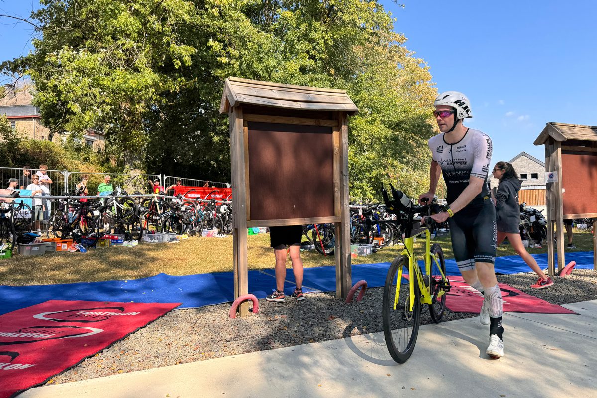Triathlet schiebt sein Fahrrad in der Wechselzone