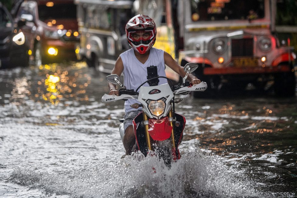Motorradfahrer fährt durch überflutete Straße in Manila