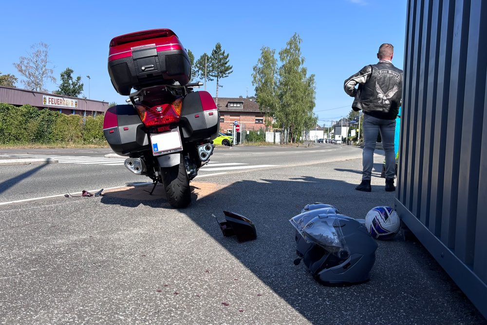 Das Unfall-Motorrad steht auf dem Bürgersteig, der Rückspiegel und Teile liegen daneben, außerdem sieht man zwei Helme und den Ball, sowie den zweiten Fahrer