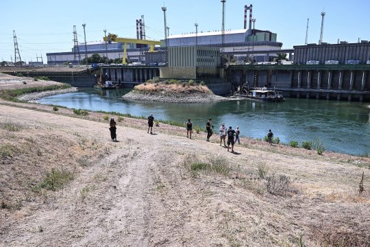 Menschen stehen am Ufer des Kühlwasserkanals am Atomkraftwerk