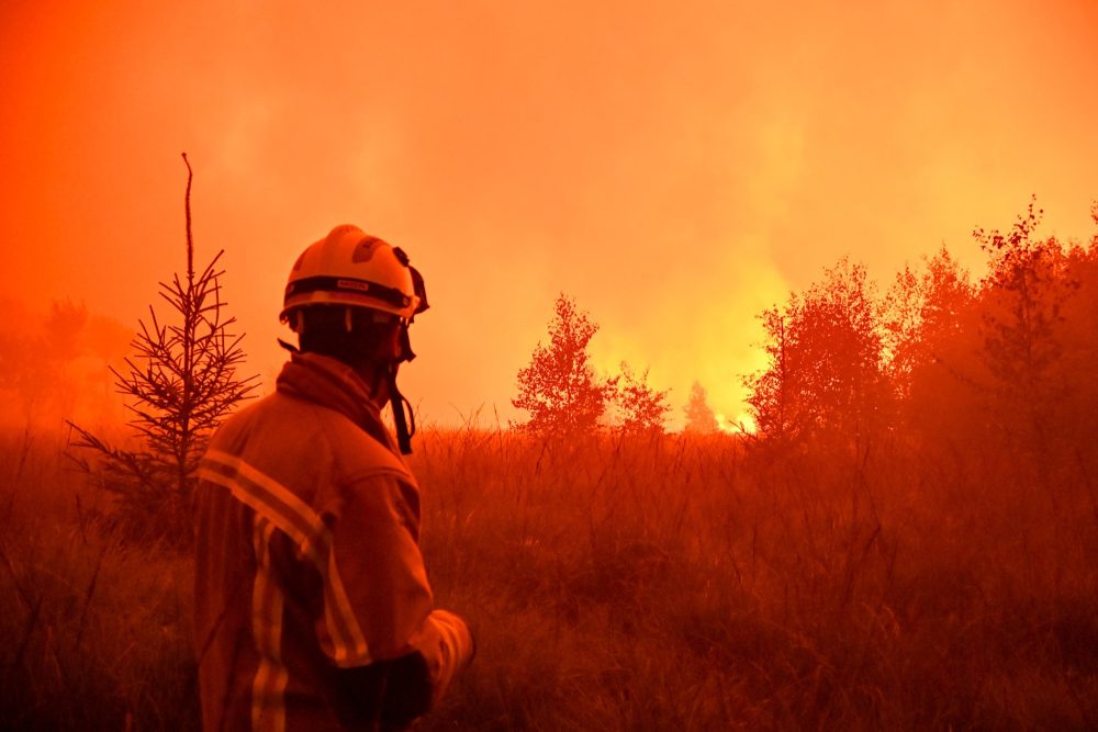 Ein Feuerwehrmann steht der riesigen Flammenfront gegenüber