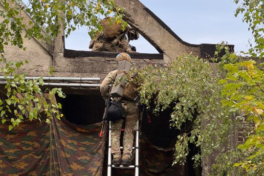 Zwei Soldaten klettern mittels einer Leiter an einer Fassade hoch