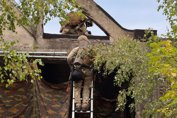 Zwei Soldaten klettern mittels einer Leiter an einer Fassade hoch