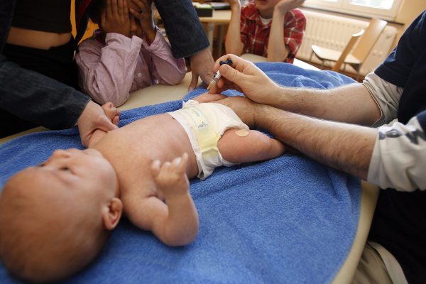ein Arzt impft ein Baby in den Oberschenkel