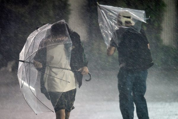 Menschen mit Regenschirmen kämpfen sich durch den heftigen Regen