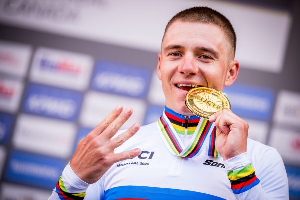 Remco Evenepoel beißt bei der Siegerehrung auf seine Goldmedaille und hält vier Finger in die Höhe