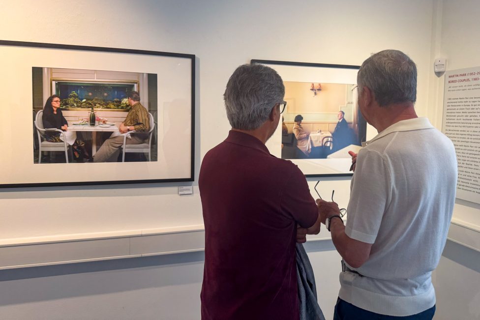 Zwei Besucher der Ausstellung schauen sich Fotos an