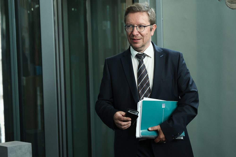 der Abgeordnete mit Akte und Mobiltelefon in der Hand