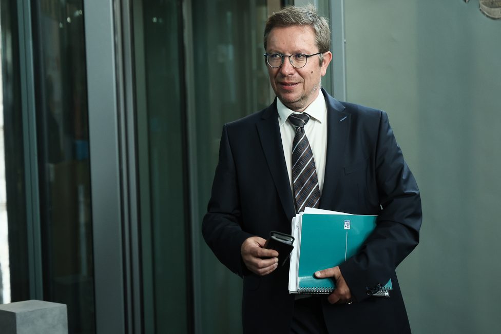 der Abgeordnete mit Akte und Mobiltelefon in der Hand