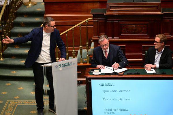Premier De Wever und Paul Magnette sitzen am Tisch und folgen den Ausführungen von Raoul Hedebouw am Rednerpult