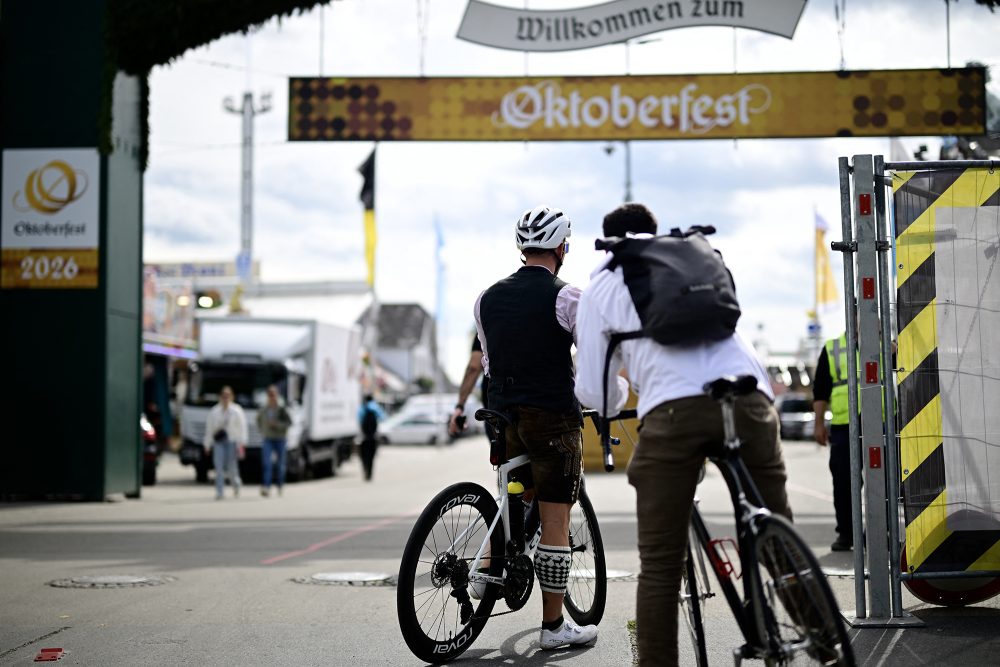 Zwei Radfahrer schauen durch den Haupteingang auf das Festgelände