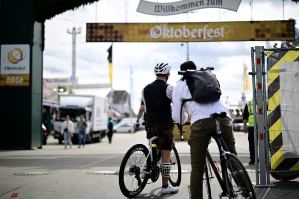 Zwei Radfahrer schauen durch den Haupteingang auf das Festgelände