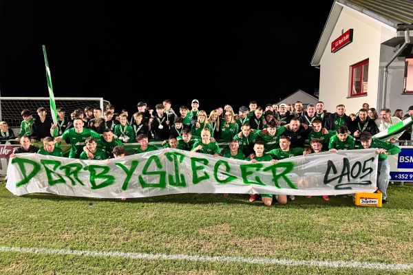 Die Ameler Mannschaft posiert fürs Gruppenfoto mit einem Banner, auf dem "Derbysieger" steht