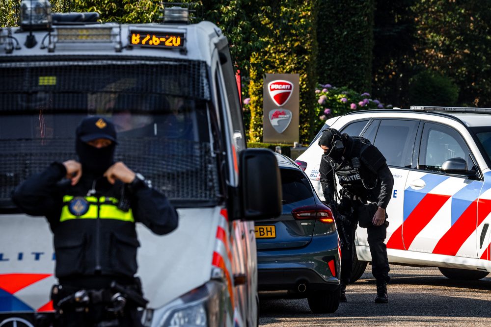 Schwer bewaffnete Polizeibeamte patrouillieren am Tatort in Overasselt